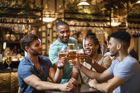 A group of male friends having a celebratory toast together with pints of beer.の写真素材
