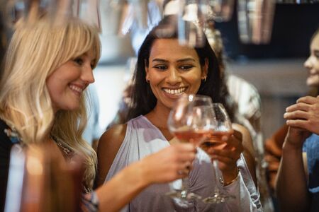 Friends drinking wine and having a celebratory toast together at a bar.