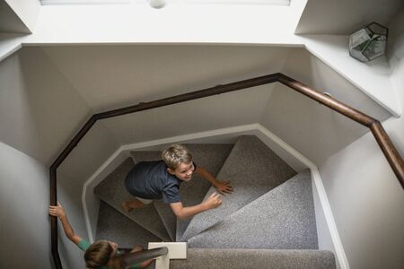 A high angle view shot of two young boys playing together, they are running up the staircase with...