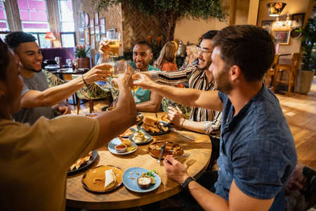 A group of males having a celebratory toast together at a table in a restaurant.の写真素材