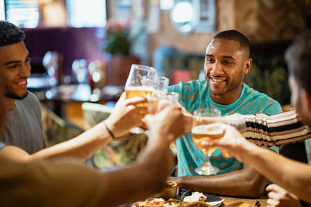 A group of male friends having a meal and celebratory toast at a restaurant.の写真素材
