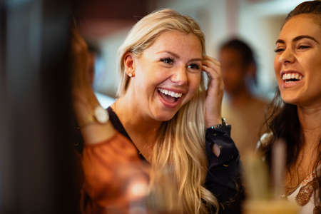A group of female friends laughing together at a bar.