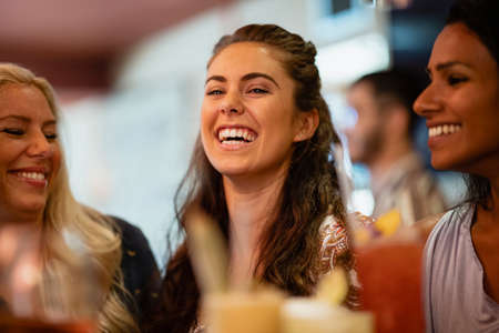 A group of female friends laughing at a bar together.の写真素材