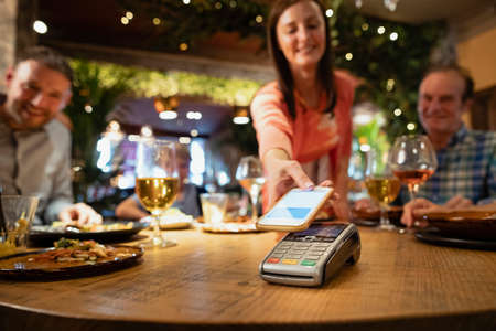 A woman paying for a meal using contactless payment through her phone.の写真素材