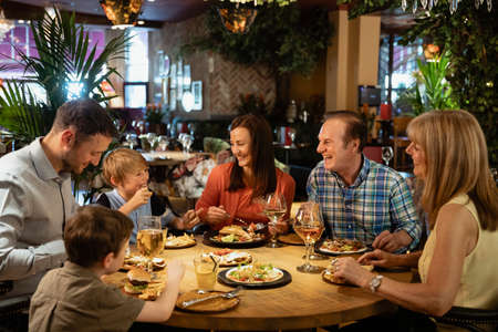 A family having a meal at a restaurant. They are laughing with each other.の写真素材