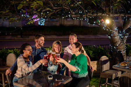 Group of diverse friends drinking champagne outdoors at a bar/restaurant, celebrating and having fun together.の写真素材