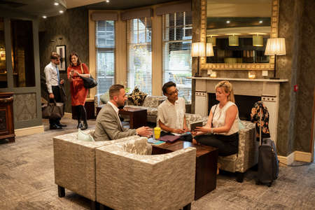 A shot of businessmen and businesswomen sitting in a lobby, they are talking business.の写真素材