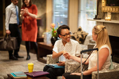 A shot of two businesswomen sitting in a lobby, they are talking business and shaking hands.の写真素材