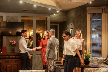 A shot of businessmen and businesswomen arriving in a lobby, they are greeting eachother with a handshake.の写真素材