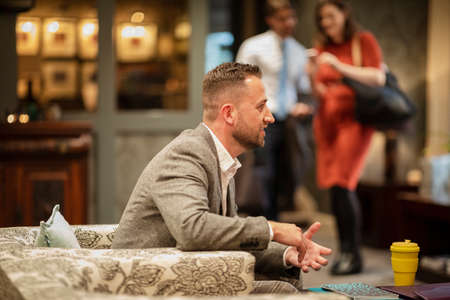 A shot of a businessman wearing smart clothing sitting in a lobby, he is talking business.の写真素材
