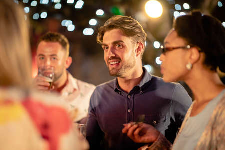 Group of diverse friends drinking champagne outdoors at a bar/restaurant, celebrating and having fun together.の写真素材