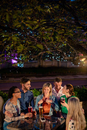 Group of diverse friends drinking champagne outdoors at a bar/restaurant, celebrating and having fun together.の写真素材