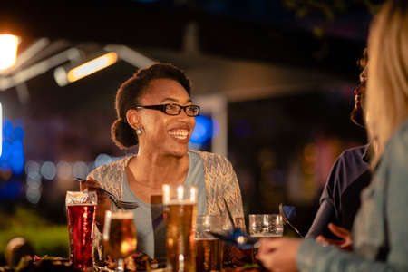 Friends drinking Alcohol outdoors at a bar/restaurant, celebrating and having fun together.の写真素材