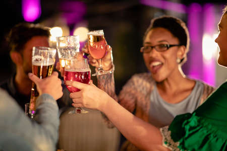 Group of diverse friends drinking champagne outdoors at a bar/restaurant, celebrating and having fun together.の写真素材