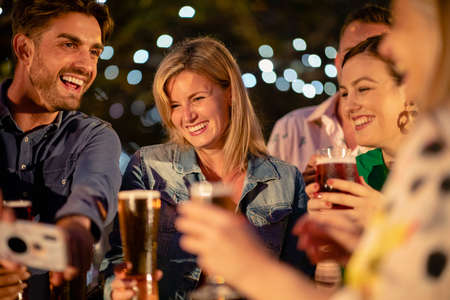 Group of friends drinking champagne outdoors at a bar/restaurant, celebrating and having fun together.の写真素材