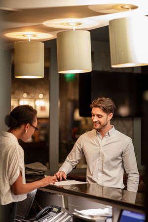A hotel receptionist talking to a customer who is checking in to the hotel.の写真素材