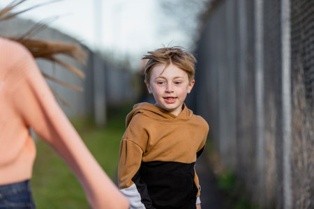 A front-view shot of a young caucasian boy wearing casual clothing, he's running outdoors.