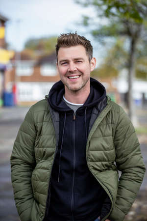 A front-view portrait shot of a mid-adult caucasian man wearing casual clothing, he's smiling and looking at the camera.の写真素材
