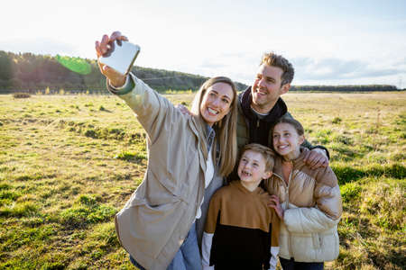 A front-view shot of a caucasian mother and father with their son and daughter, they're all taking a...