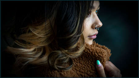 Side view of a young contented, trendy woman. She is posing for the camera.の写真素材