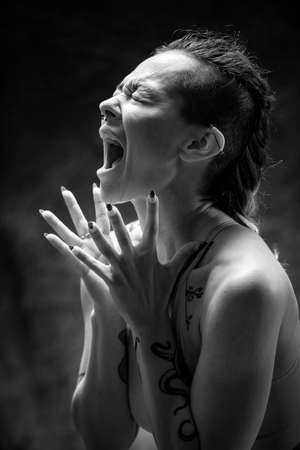 A young woman wearing gymwear, standing in front of a backdrop. She is screaming out loud and her hands are outstretched.の写真素材