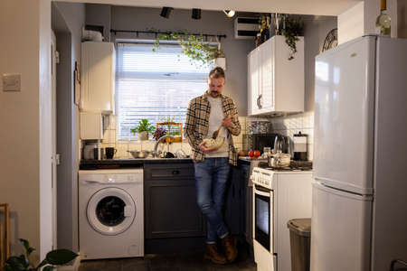 A front-view shot of a caucasian man standing in his kitchen, he is making pasta for lunch.の写真素材