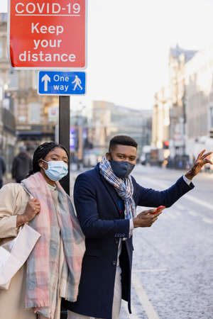 Couple wearing face coverings in town waiting for cabの写真素材