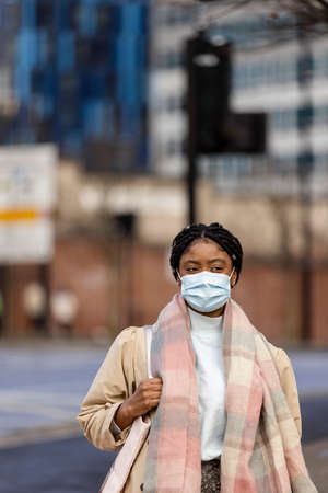 Woman with face covering walking through townの写真素材