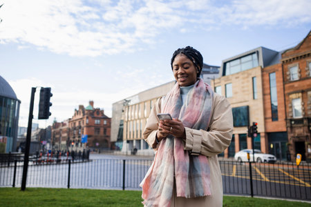 Woman smiling and using mobile in town centre with road in backgroundの写真素材