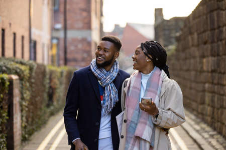 Cheerful couple walking down back lane chatting and looking at buildingsの写真素材