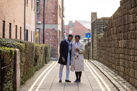 Couple using mobile phone on back lane in city, checking directionsの写真素材