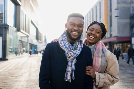 Cheerful couple smiling towards camera out and about in the city centreの写真素材