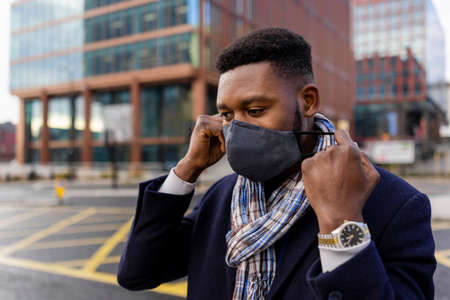 Man taking off face covering in cityの写真素材