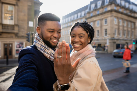 Cheerful couple in town, woman holging hand up to show engagement ringの写真素材