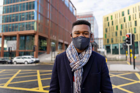 Man with face covering looking at camera with buildings in backgroundの写真素材