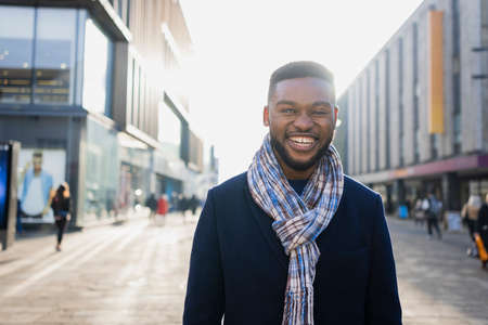 Cheerful man with beard out and about in the city centre looking at cameraの写真素材