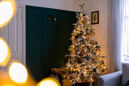 A wide shot of a Christmas tree decorated with golden-orange shiny balls and lights in a living room.の写真素材