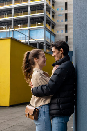 A side-view shot of a young couple standing face to face together against a wall, they are embracing and they're in love.の写真素材