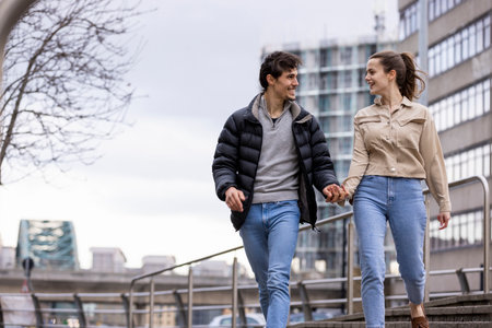 A wide-view shot of a young couple walking side by side together, they are holding hands and they're in love.の写真素材