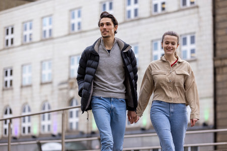 A wide-view shot of a young couple walking side by side together, they are holding hands and they're in love.の写真素材