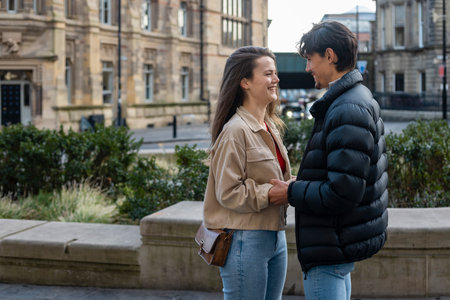 A wide-view shot of a young couple standing face to face together, they are holding hands and they're in love.の写真素材