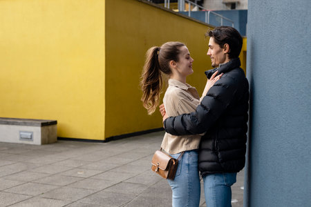 A side-view shot of a young couple standing face to face together against a wall, they are embracing and they're in love.の写真素材