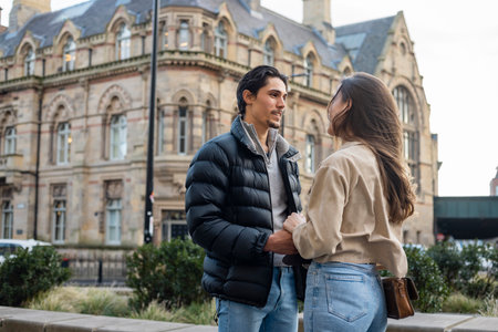 A wide-view shot of a young couple standing face to face together, they are holding hands and they're in love.の写真素材