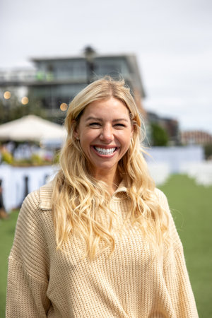 Front-view portrait of a mid adult woman standing in a city centre street, in Newcastle, England. She is wearing casual clothing and standing, smiling and looking at the camera.の写真素材