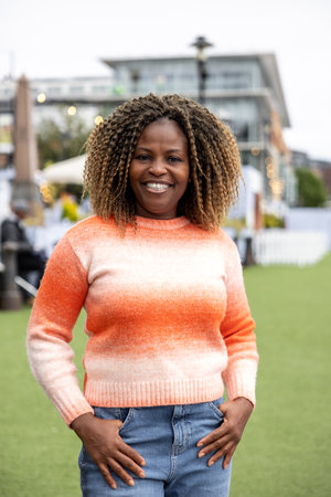 Front-view portrait of a mid adult woman standing in a city centre street, in Newcastle, England. She is wearing casual clothing and standing, smiling and looking at the camera.の写真素材
