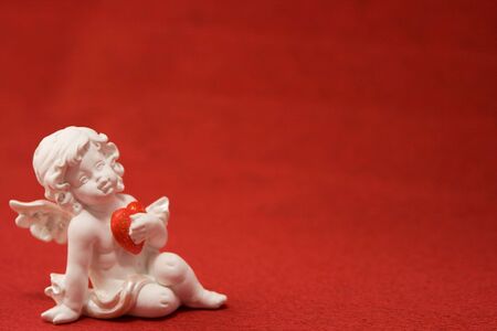 The white cupid with heart on a red background. Valentines day card.の写真素材