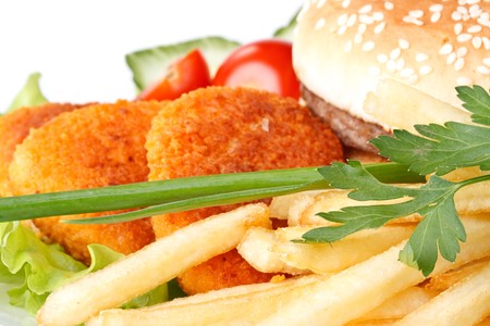 Hamburger, french fries, chicken nuggets, and vegetables on a white background
