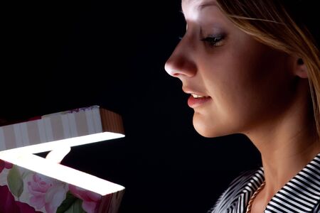 The girl opens a gift on a black background.の写真素材