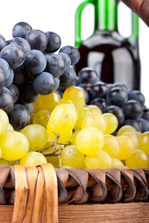 Appetizing grapes in a basket and bottle of wine on a white background.の写真素材