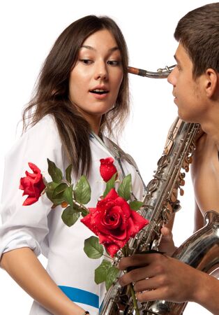 The male  patient gives a flower to the beautiful female doctor with a saxophone on a white background.の写真素材